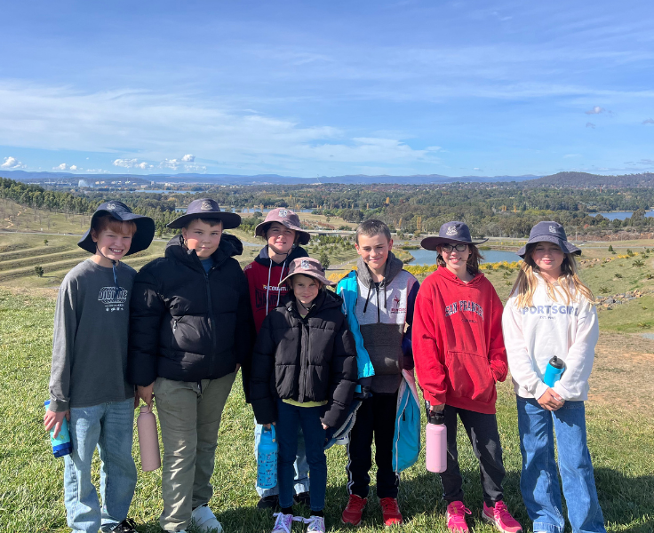 7 students smiling whilst standing on a hill with a view behind them