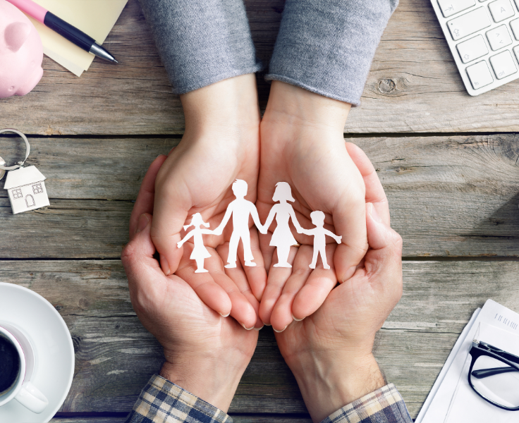 Two hands holding a paper cutout of a family