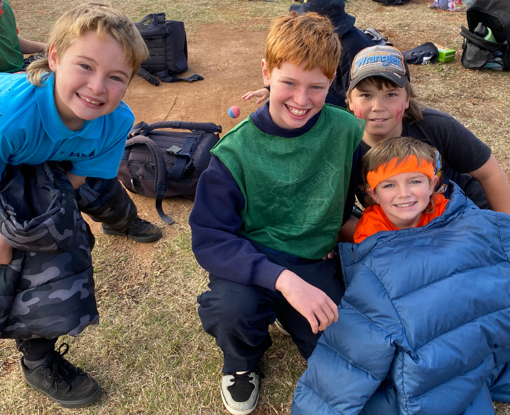 4 Students smiling whilst sitting on an oval