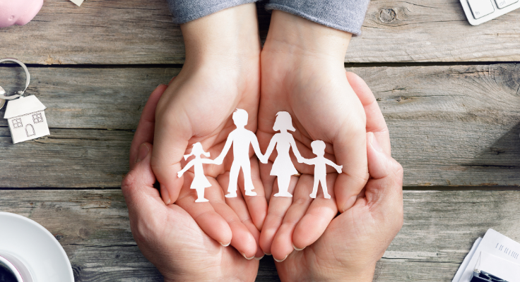 Two hands holding a paper cutout of a family